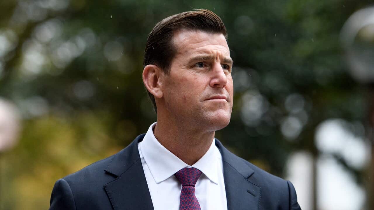 A man in a blue suit, white shirt and blue and red tie