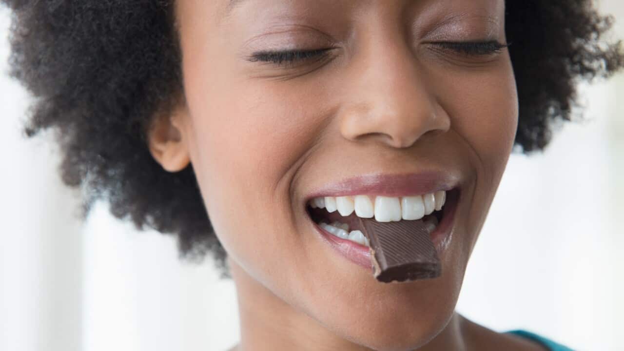 Close up of African American woman eating square of chocolate