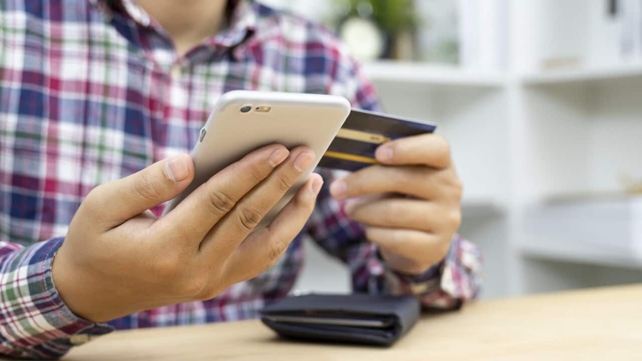 Young man hands holding credit card and using phone