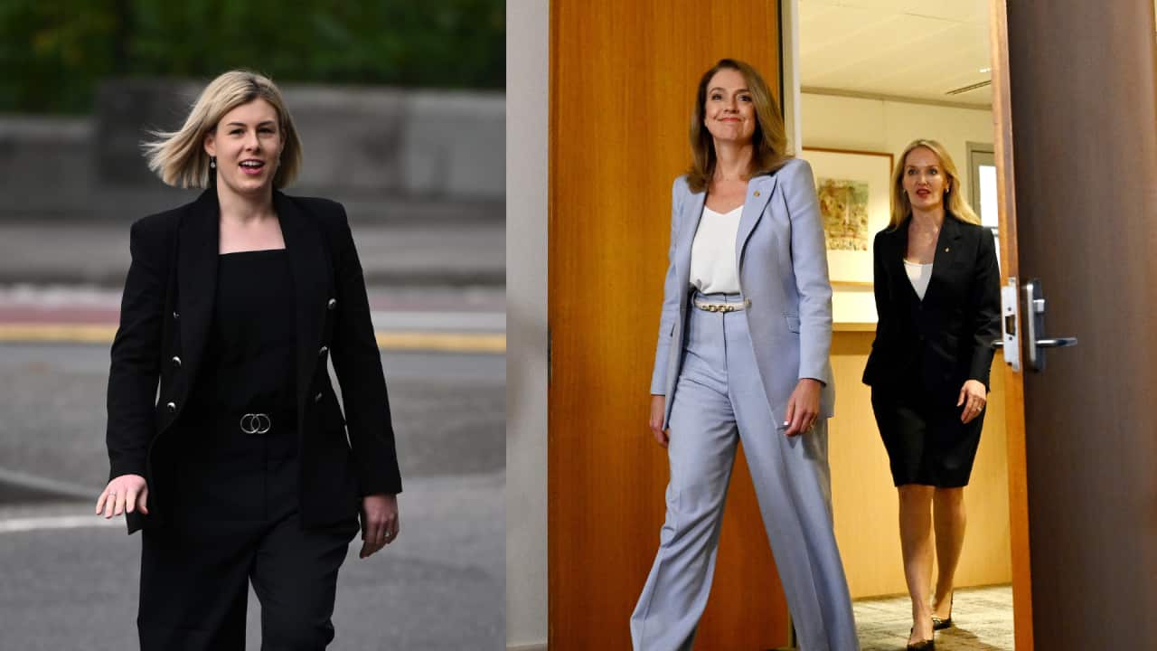 On the left, a woman with short blonde hair in a black suit. On the right, a woman in a lavender suit entering a room.