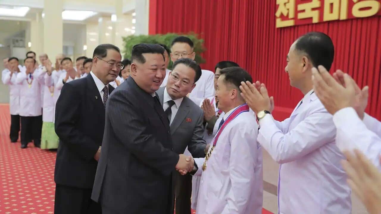 North Korean leader Kim Jong Un shakes hands with a health official in Pyongyang, North Korea, on Wednesday, 10 August 2022. Mr Kim has declared victory over COVID-19 and ordered an easing of preventive measures.