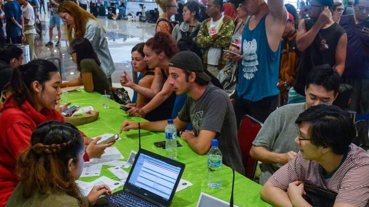 Stranded tourists line up to change their return ticket in Denpasar