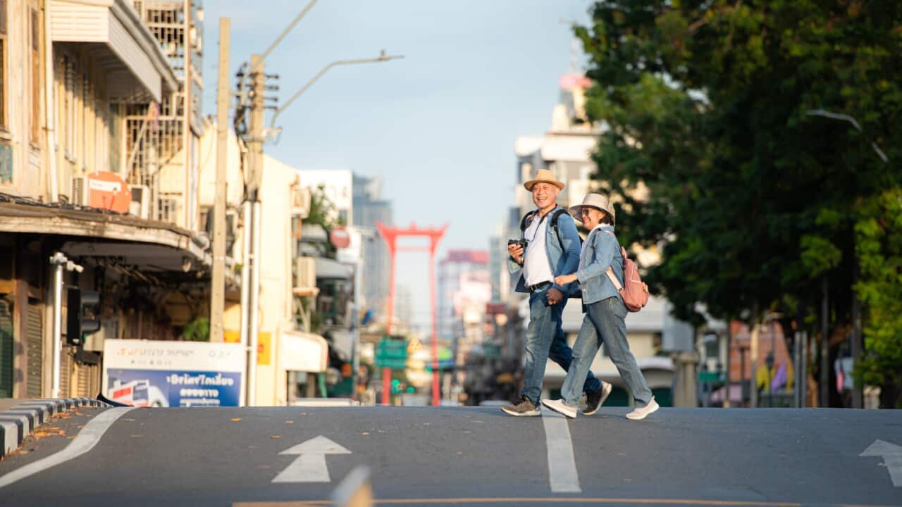 An elderly couple walks around the street.