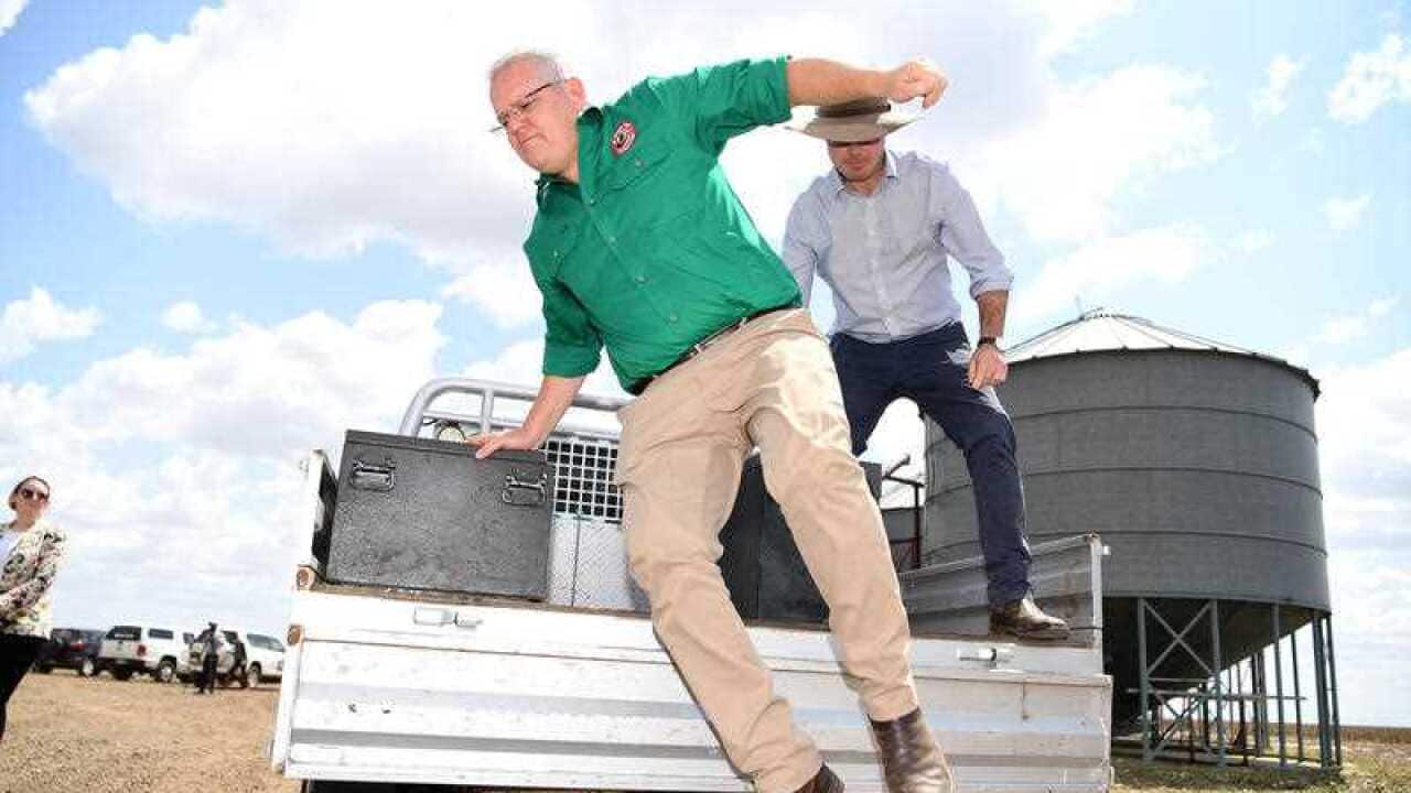 Prime Minister Scott Morrison jumps off a ute during a visit to a drought-affected property near Dalby, Queensland.