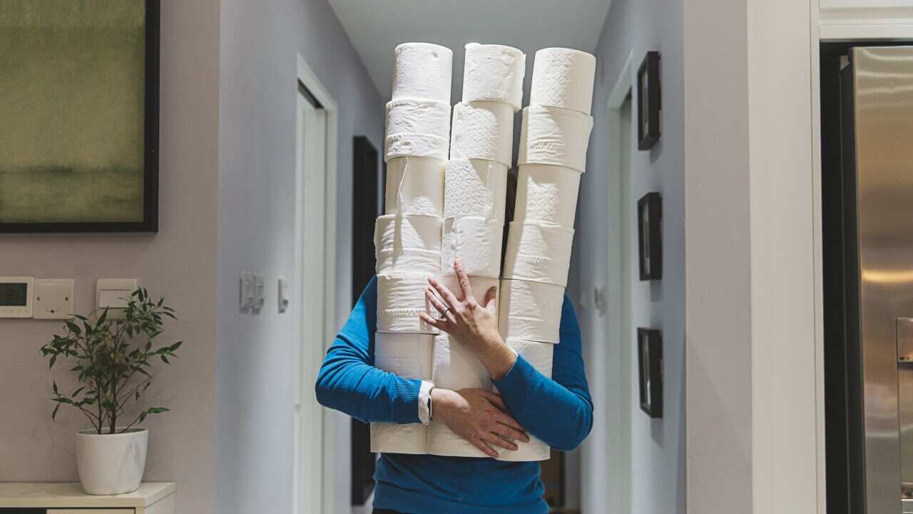 Person holding large piles of toilet rolls
