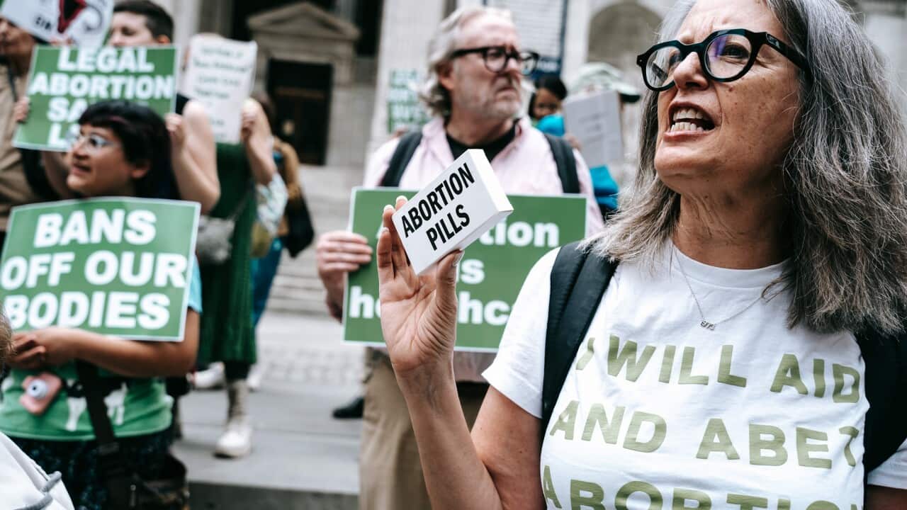 An abortion rights supporter holds up a box labeled "abortion pills" at a rally in New York.