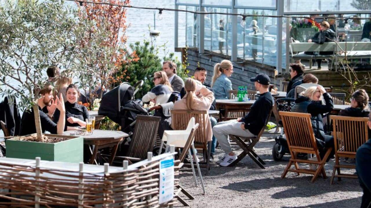 People sit in the spring sun at an outdoor restaurant in Stockholm, Sweden on 26 April, 2020.
