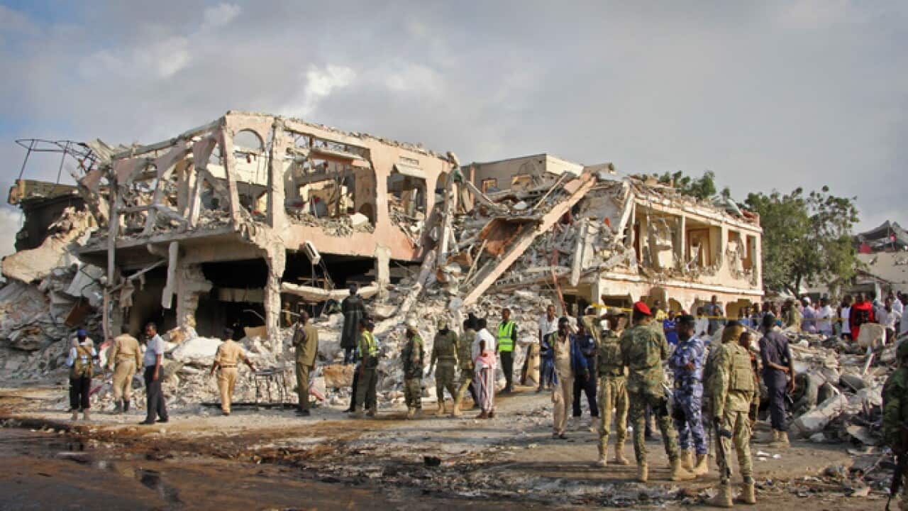 Somali security forces and others survey the damage of twin bombings