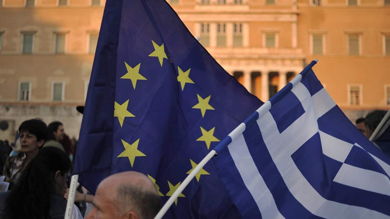 A demonstrator waves Greek and pro Euro flags.