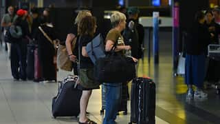 People with suitcases in the departures hall at an airport.