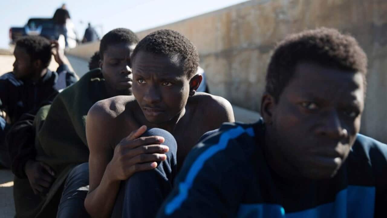 (File image of )Migrants rest on the sidewalk port of Tripoli