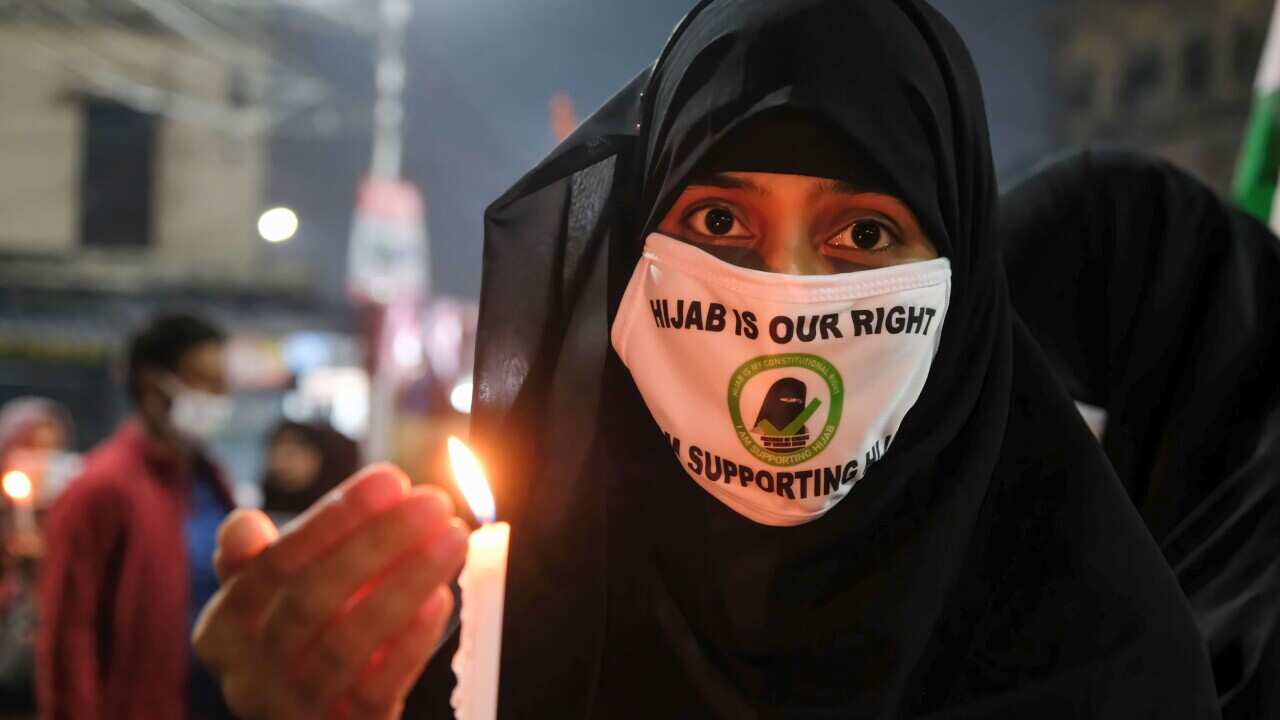 Eine mit Burka bekleidete muslimische Frau hält während einer Demonstration eine brennende Kerze in der Hand