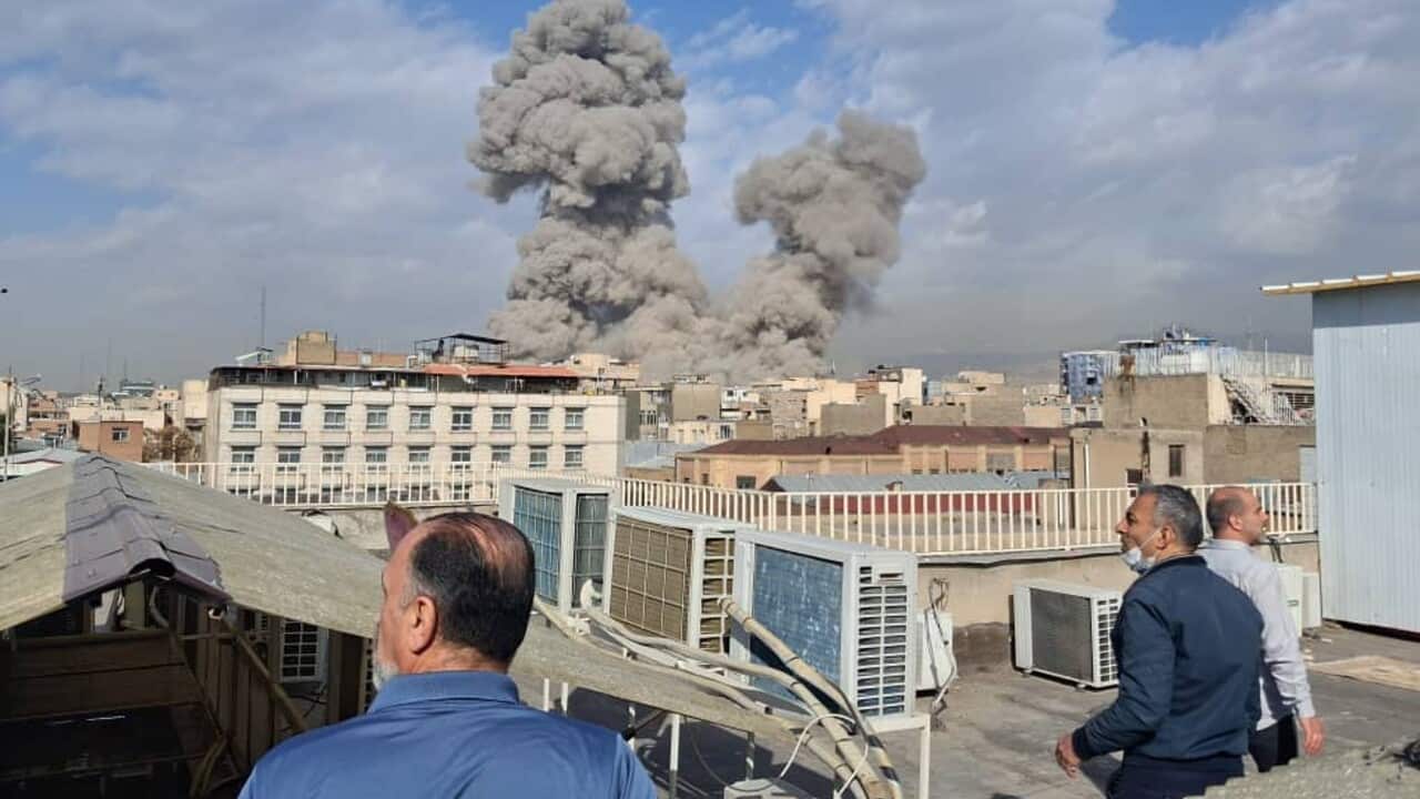 People watch as smoke rises on the skyline after an explosion.