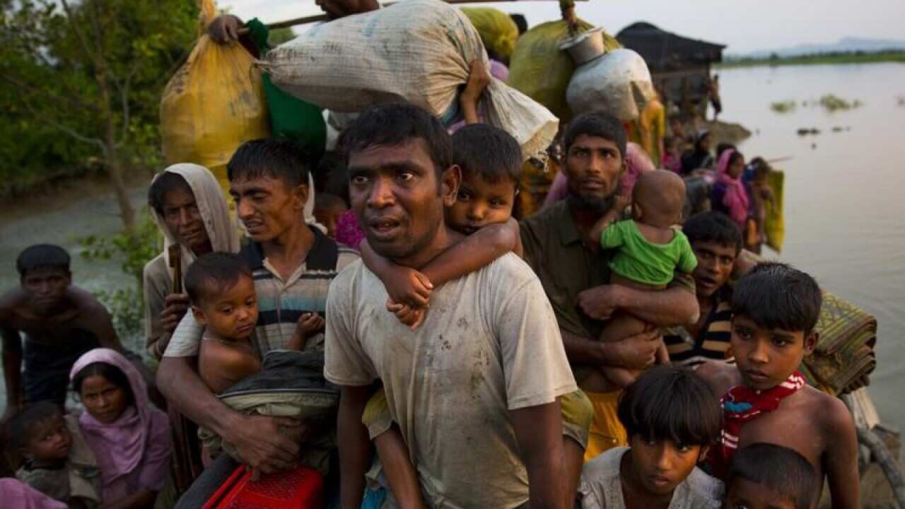 File image of Rohingya Muslims carry their young children over water.