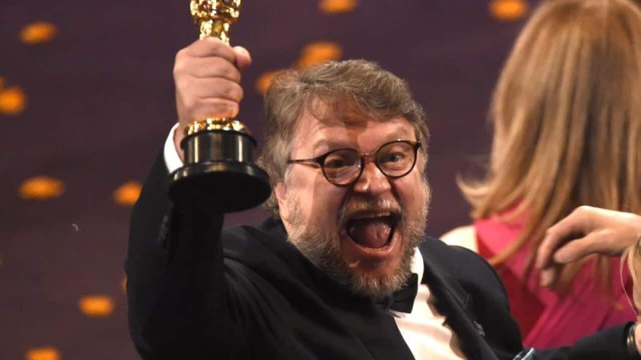 Guillermo del Toro holds up his best director Oscar trophy.