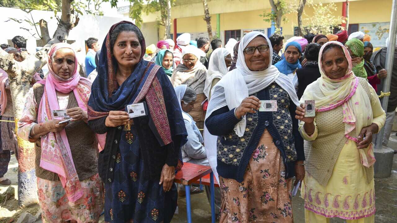 Village women display their voter identity cards as they arrive to cast their votes for the Punjab State Assembly elections in village Jagdev Kalan, outskirts of Amritsar, India, Sunday, Feb. 20, 2022. (AP Photo/Prabhjot Gill)
