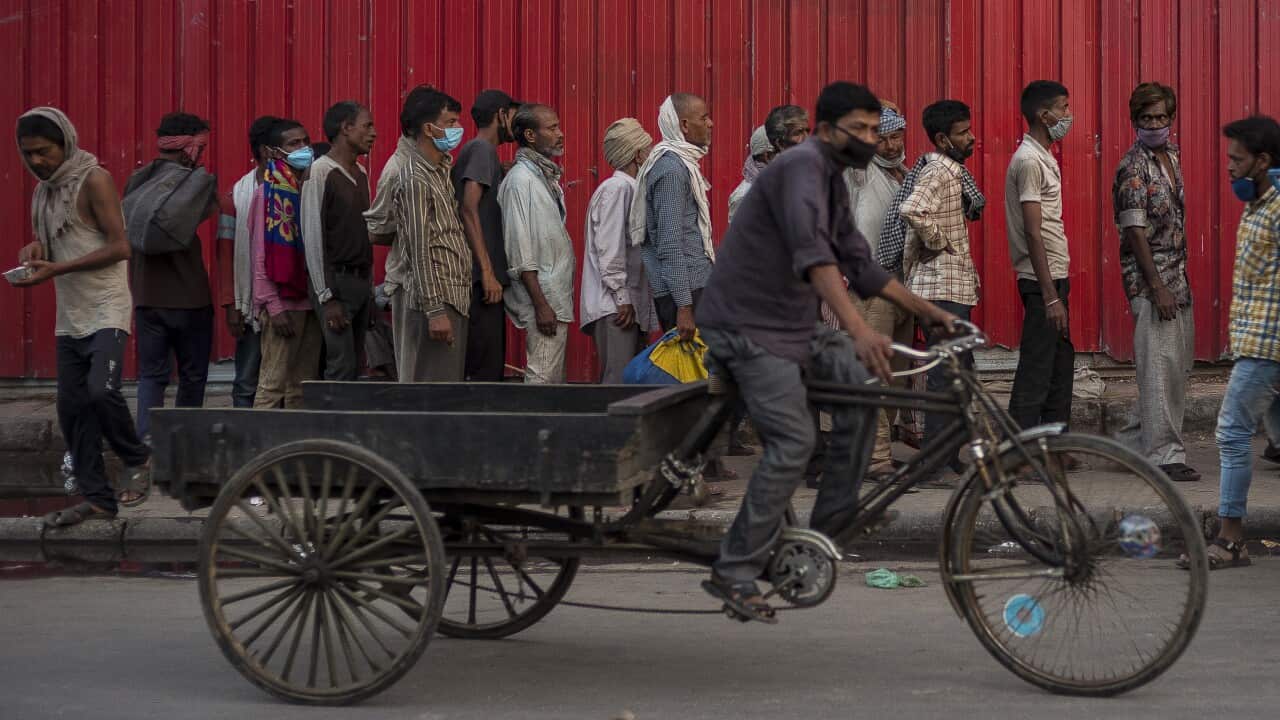 Rickshaw-pullers and other migrant laborers queue up to receive food distributed by a charity amid lockdown in New Delhi.