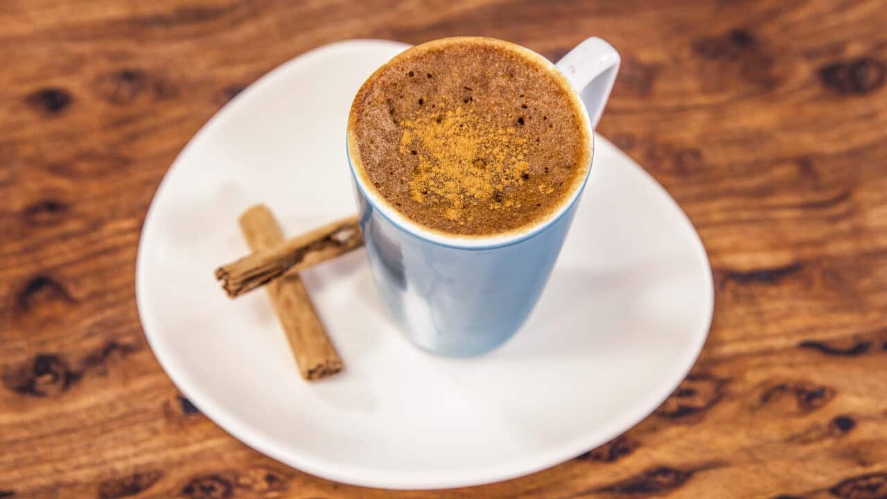A blue coffee mug, holding a 'mug cake', sits on a white plate on a wooden surface.