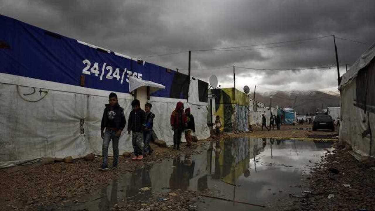 Syrian refugee children walk in mud after a heavy rain at a refugee camp in the town of Bar Elias, in Lebanon.