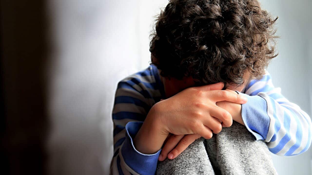 Boy Praying With Hands Over Face Against Wall At Home Stock Photo