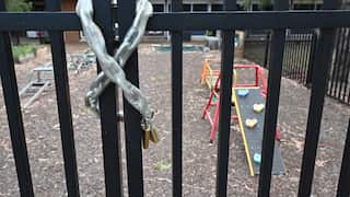 A gate with a chain and padlock around it, in front of play equipment.
