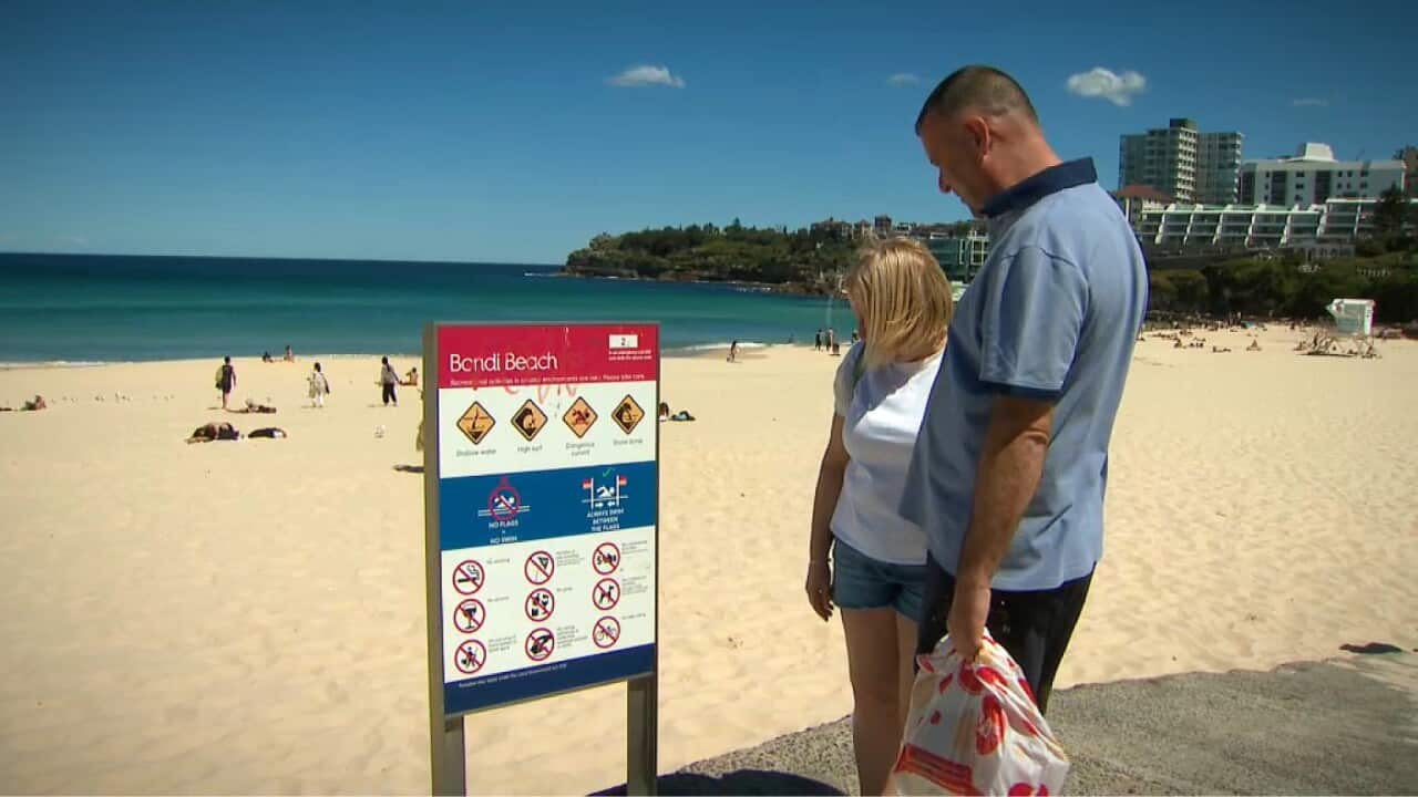 Two people look at a beach sign.