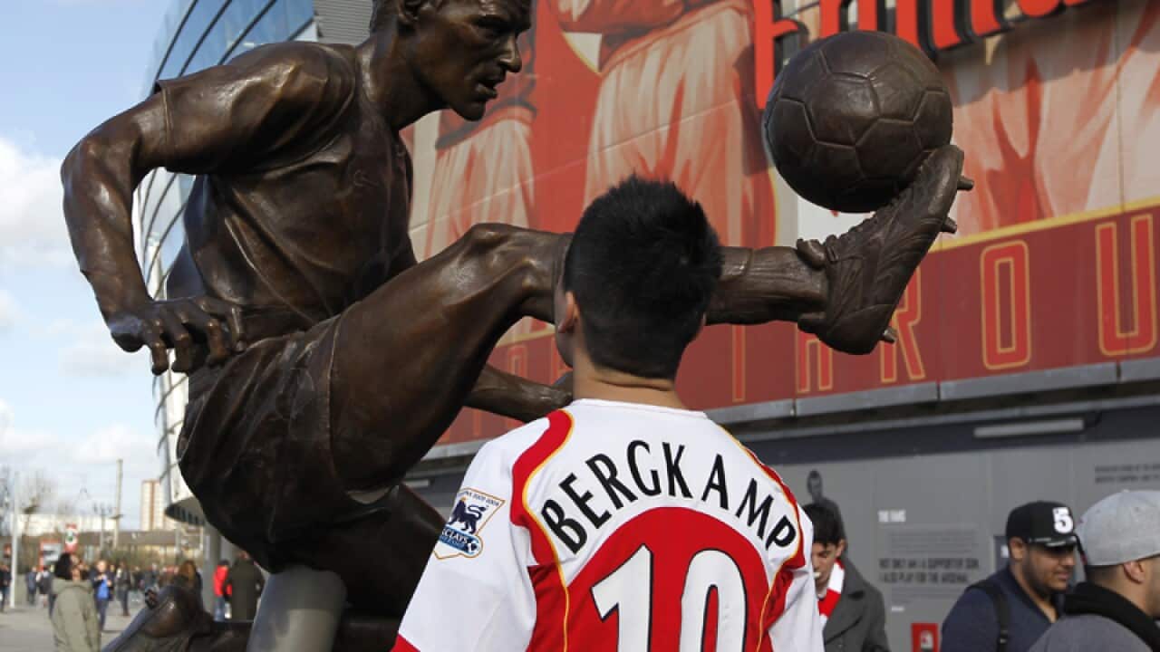 A fan looks at a statue of former Arsenal footballer Dennis Bergkamp