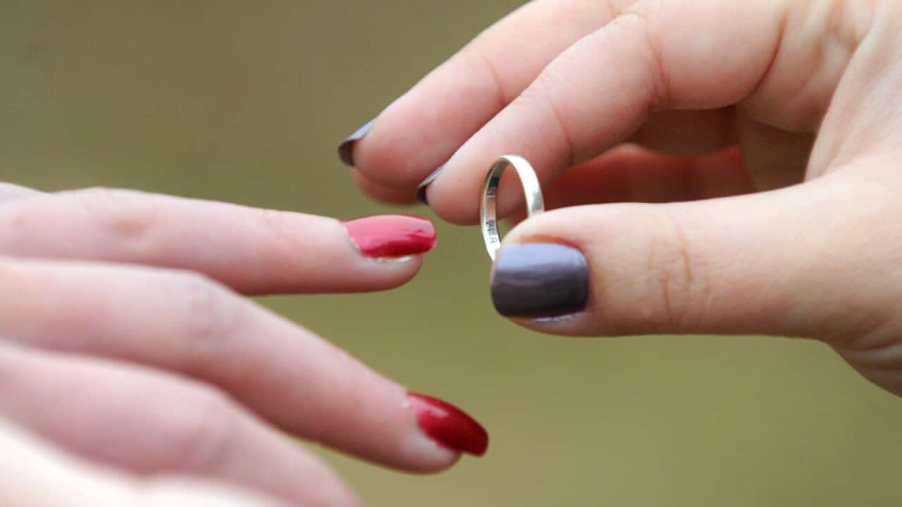 A woman places a wedding ring on her partners finger in Canberra