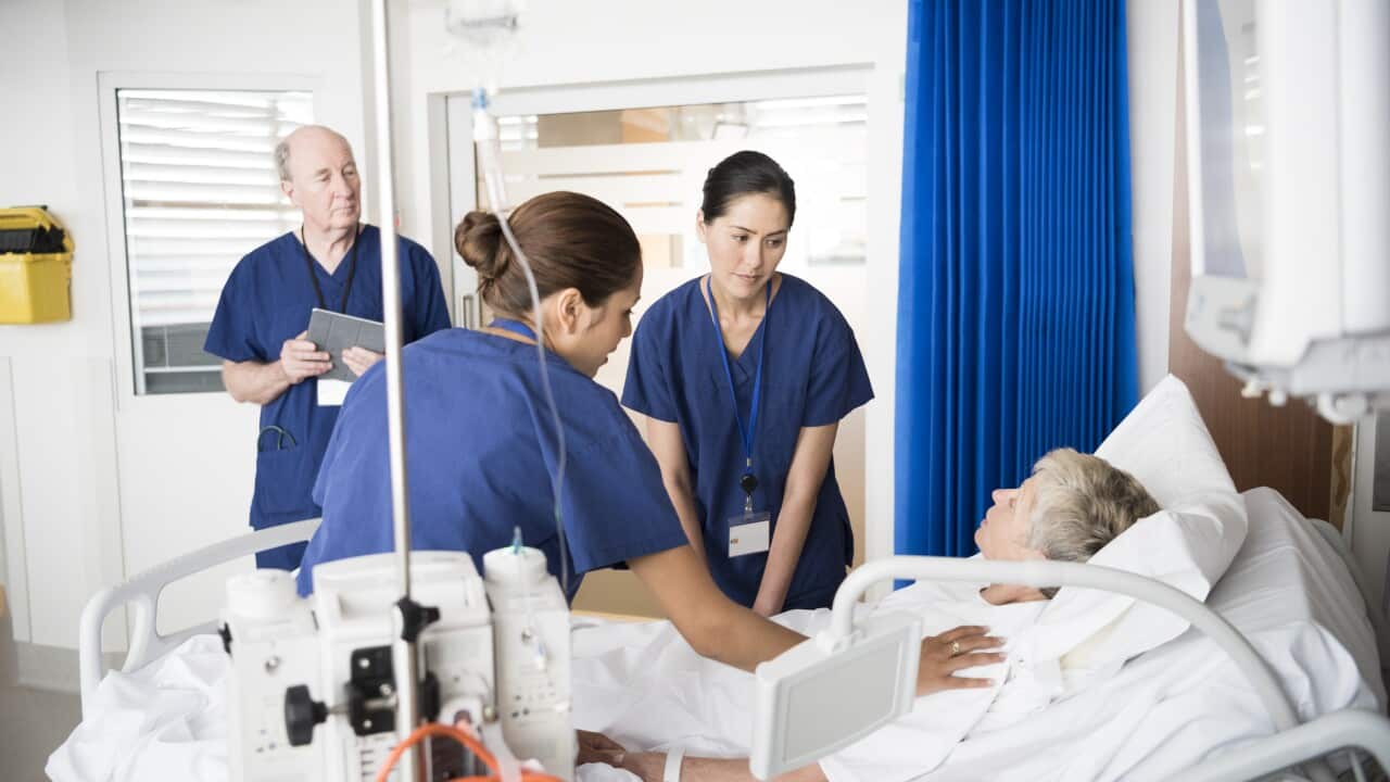 Senior female patient in bed with concerned medical staff