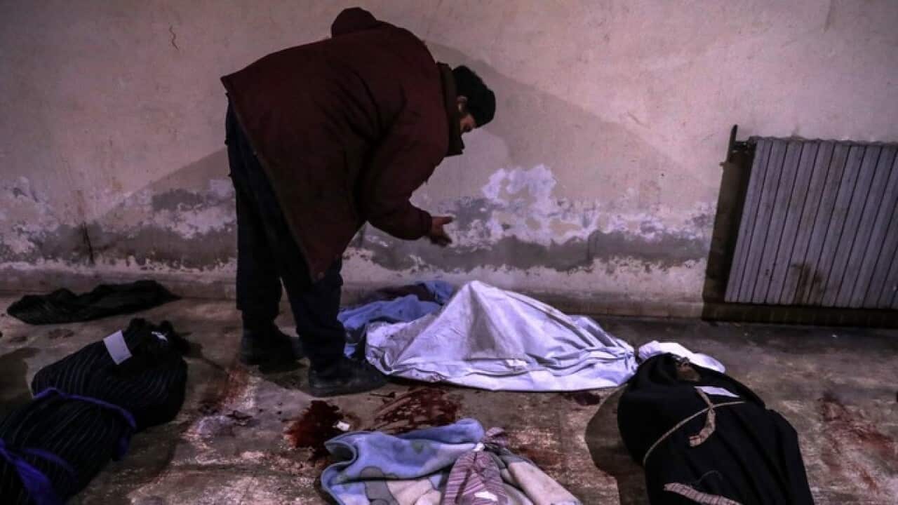 A Syrian man reacts at the body of a child at a morgue