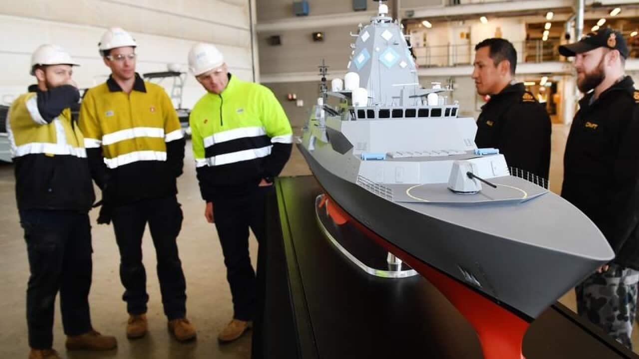 ASC workers are seen near a model of a ship.