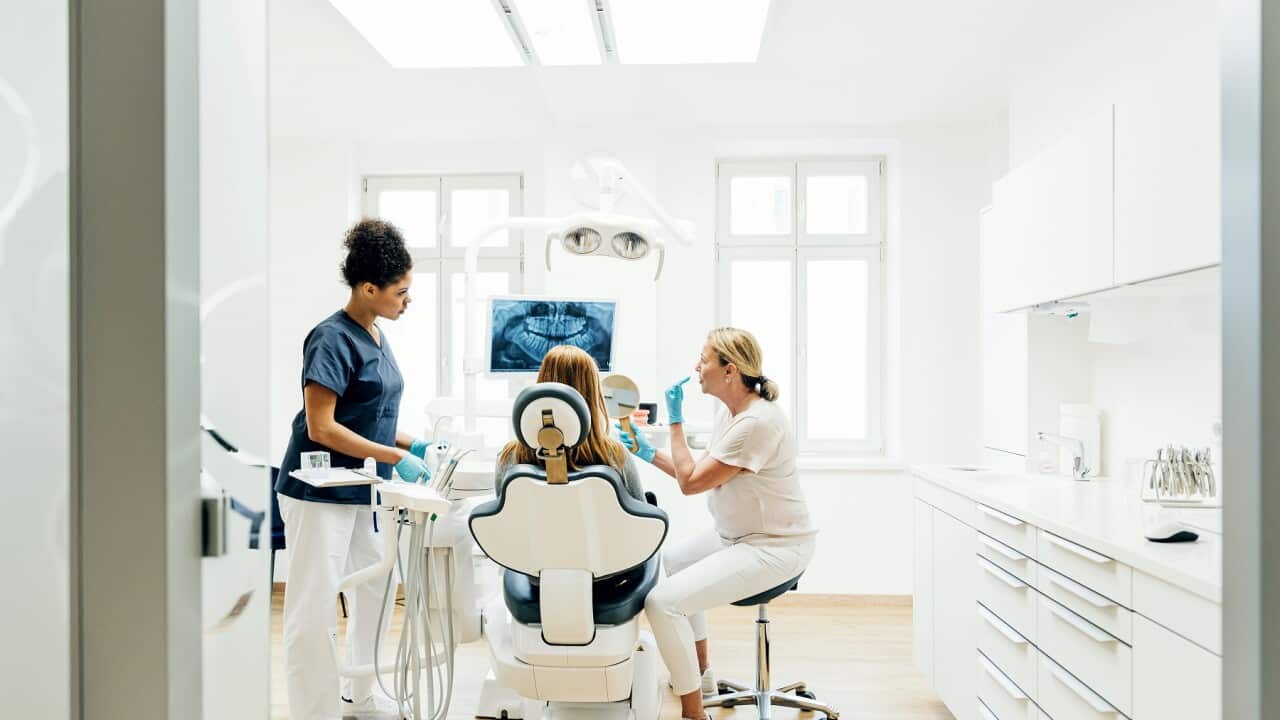 Orthodontist Showing Patient X-Ray Of Teeth In Surgery