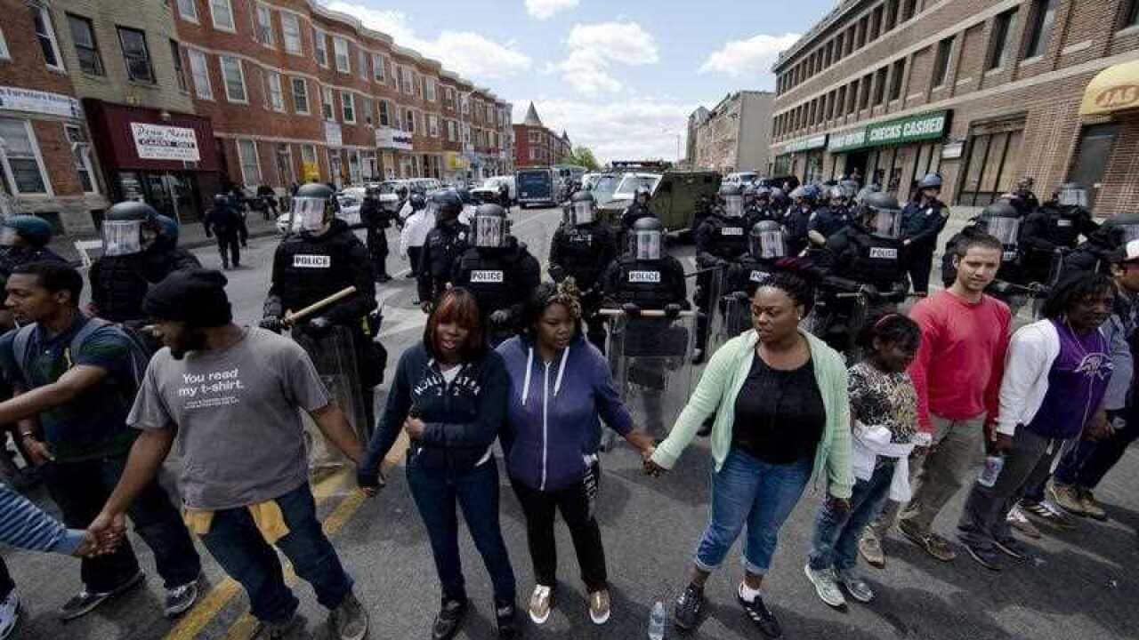 People clasp hand and sing the hymn "Amazing Grace in Baltimore, in the aftermath of rioting (AAP)