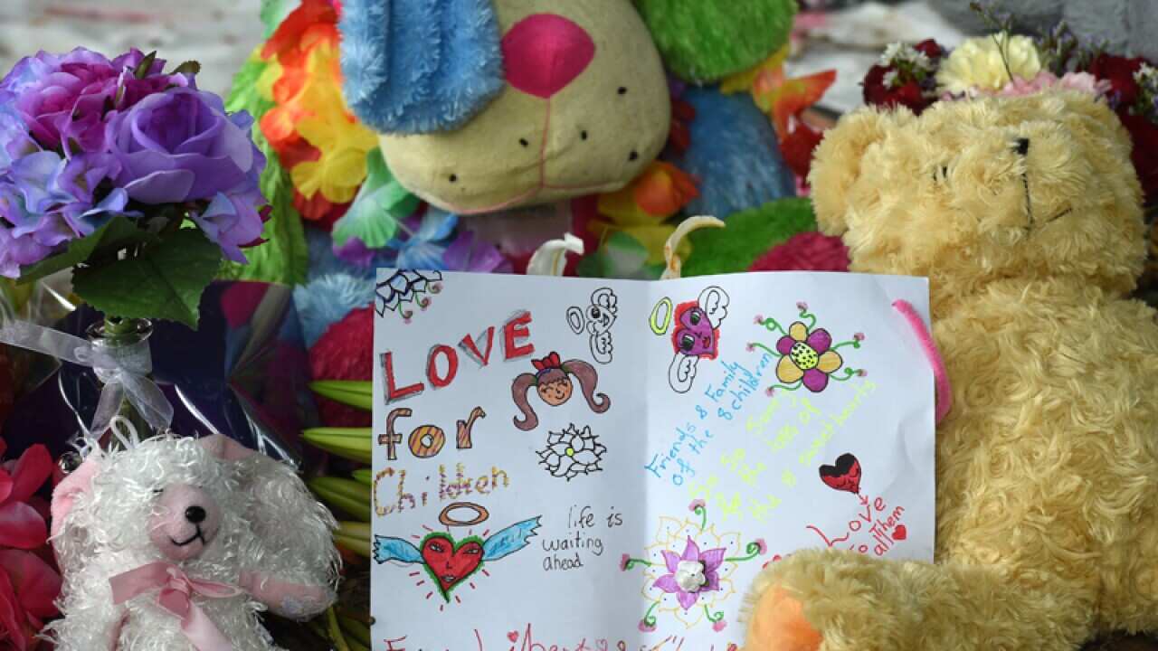 Stuffed teddy bears and a card is seen at a makeshift memorial
