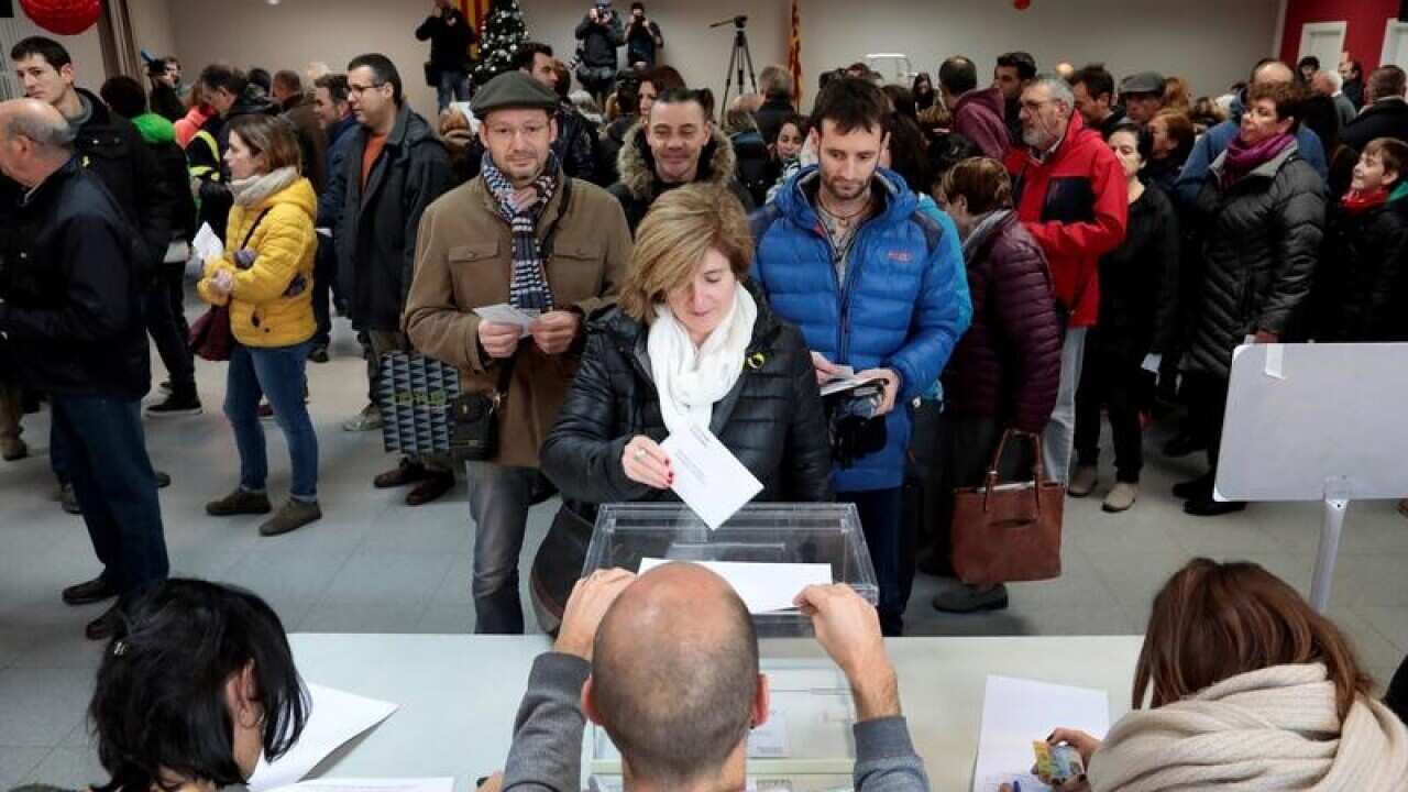 A voter (C) casts her ballot in a polling station in Vic, Barcelona.