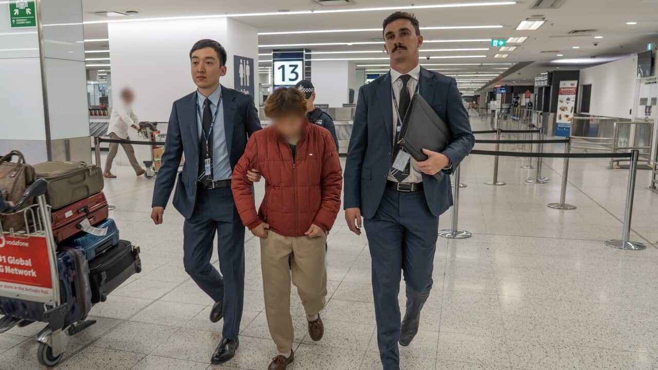 Two detectives in suits hold a woman by the arms. Her face has been blurred