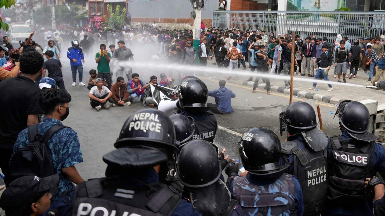 Police hitting protesters with a water cannon.