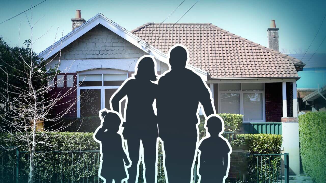 A family of parents and two children silhouetted in front of a house