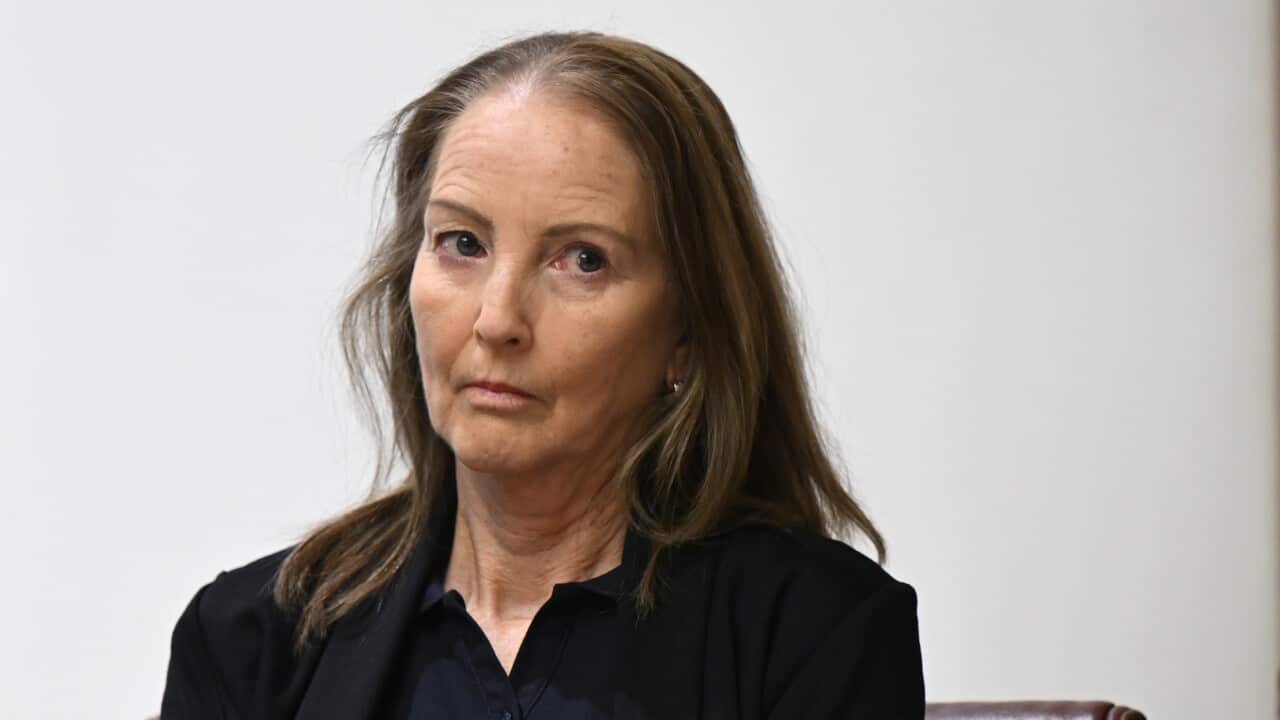 A woman with long brown hair wearing dark clothing
