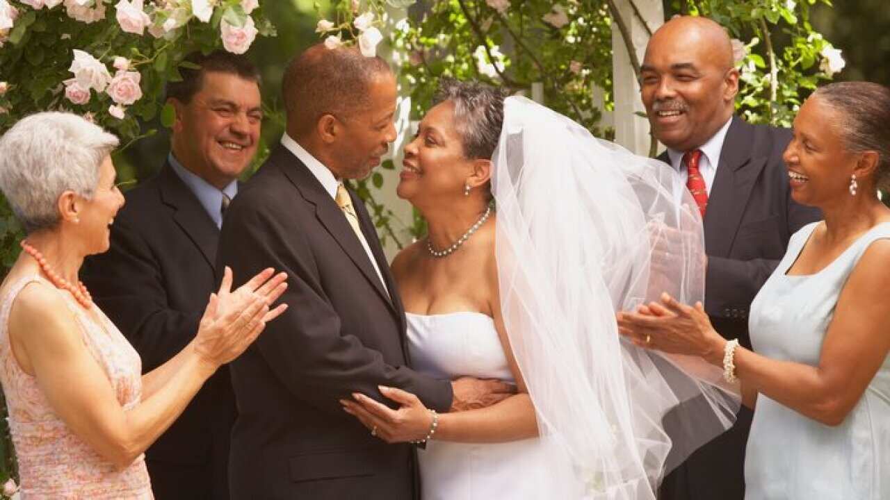 Middle-aged African bride and groom hugging