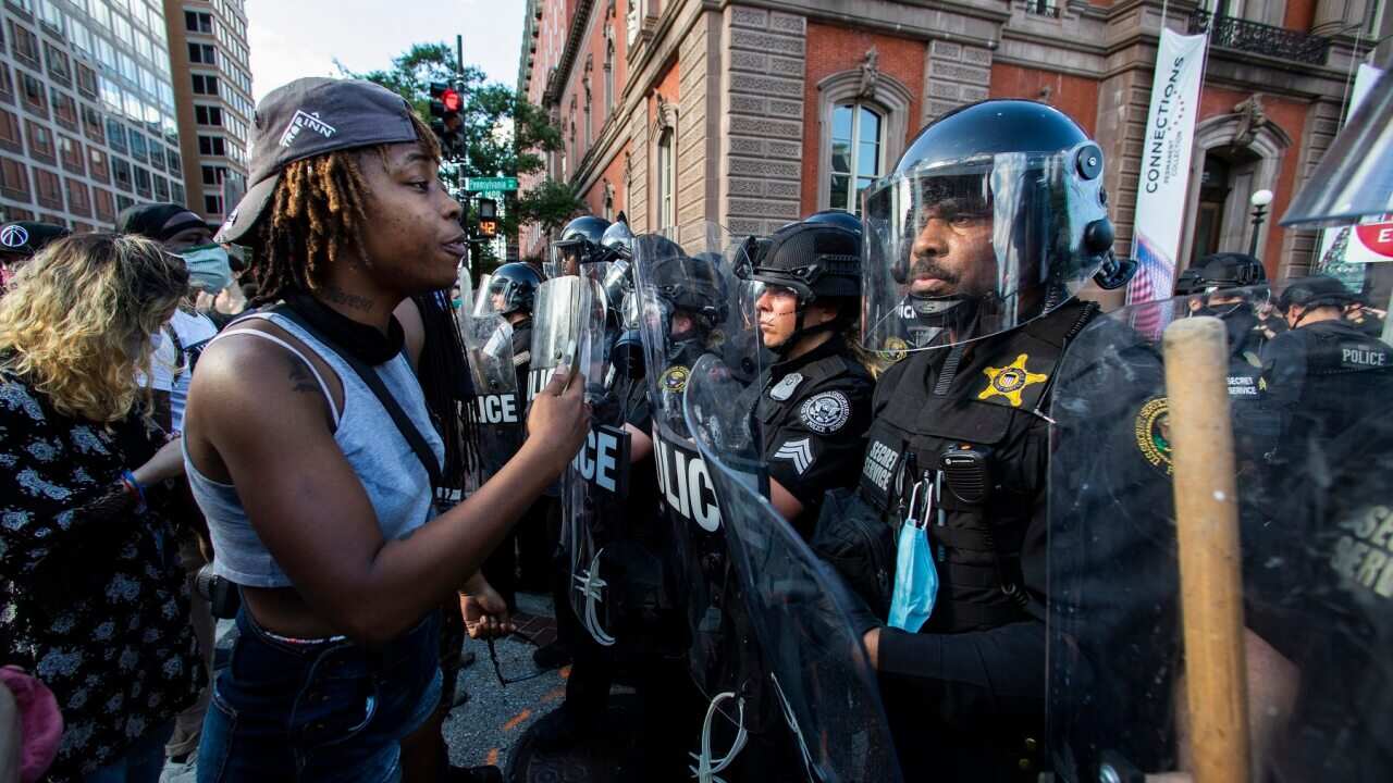 Protesters confront police in riot gear near the White House in Washington.