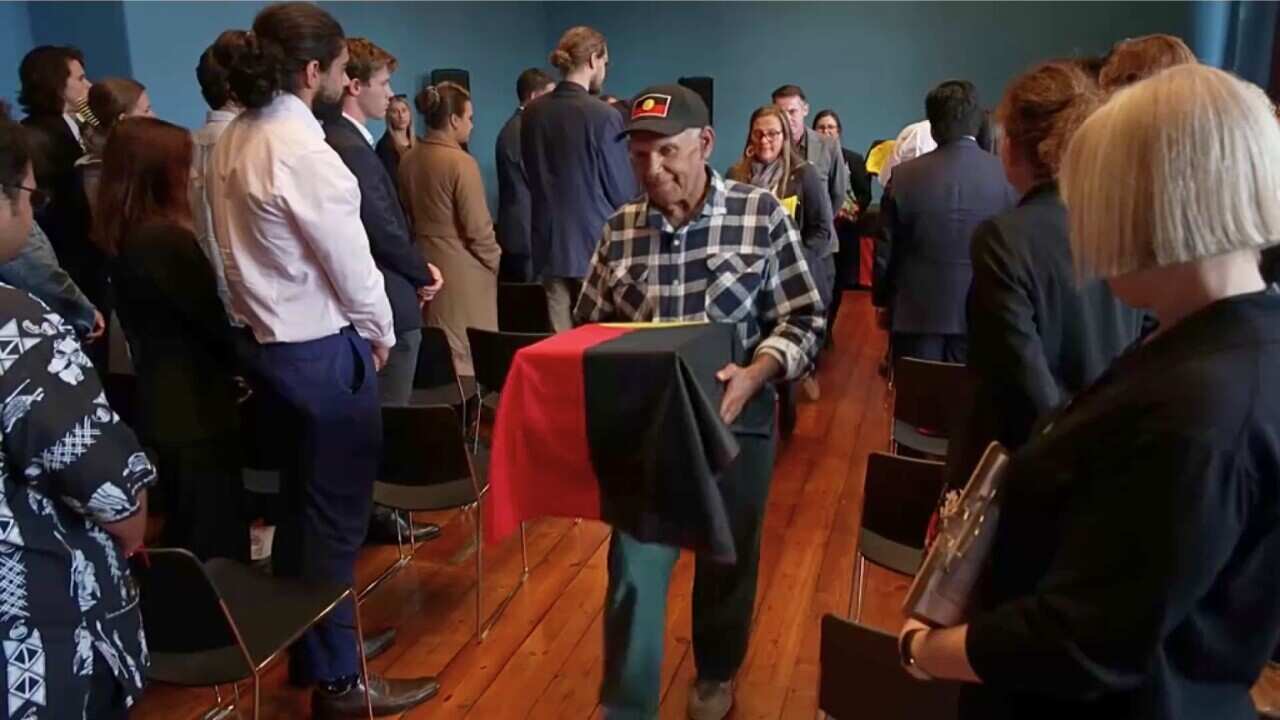 Aboriginal and Torres Strait Islander representatives walking out with boxes holding the remains of 11 ancestors (NITV).jpg