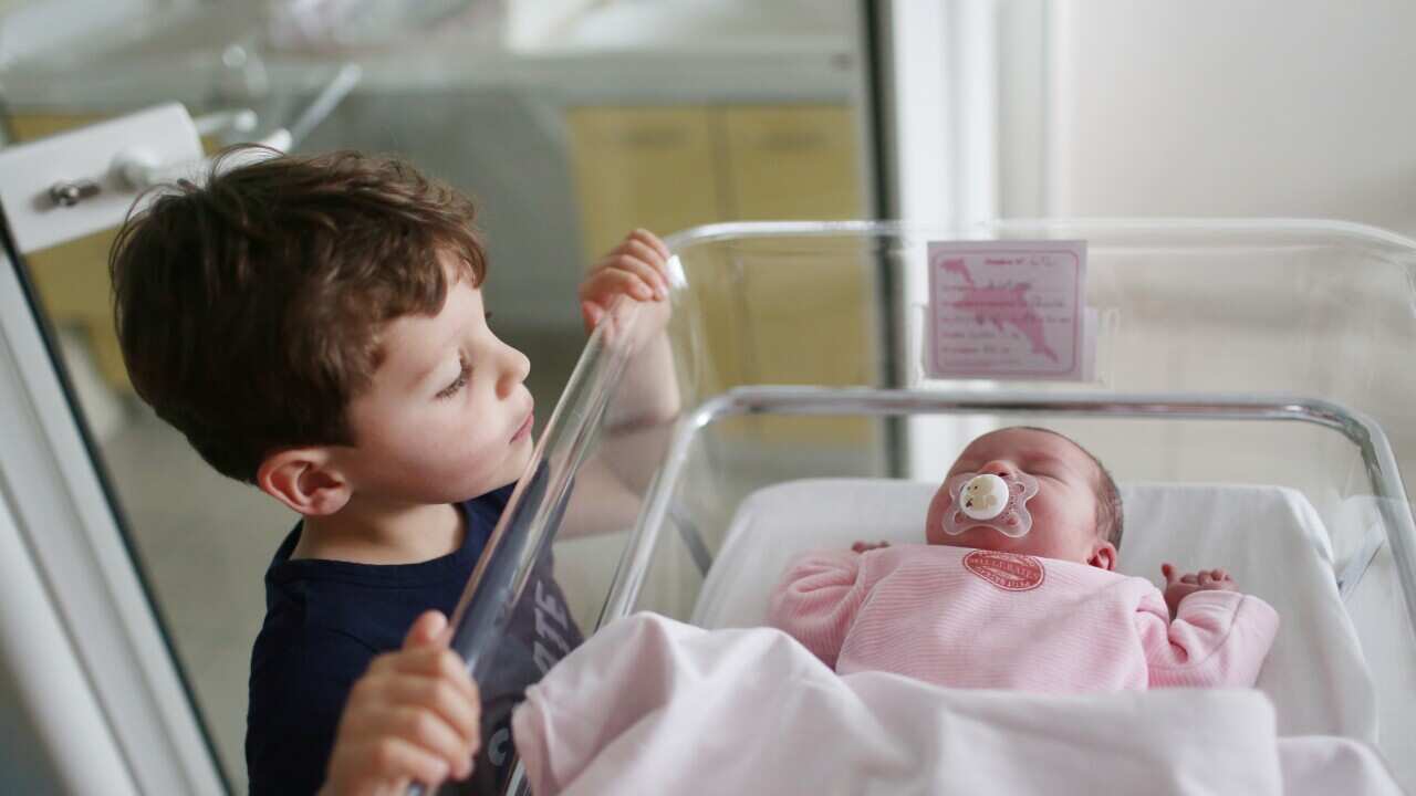 A newborn with her brother at the maternity ward