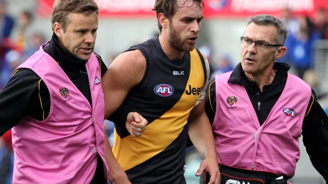 Richmond's Ben Griffiths is assisted from the ground by club trainers