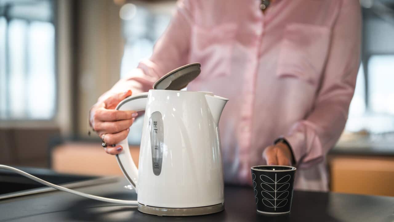 Caucasian Female Office Employee Using An Electric Kettle At Work
