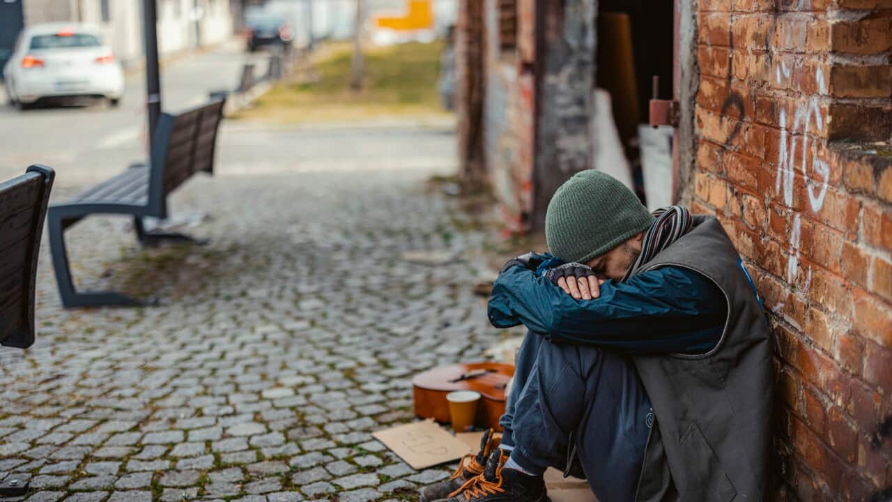 A young man sitting on the street with his head down