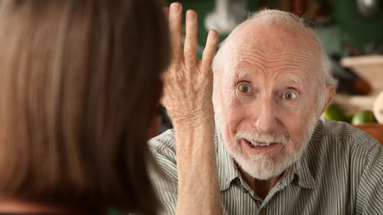Senior man holding his arm up to woman facing him