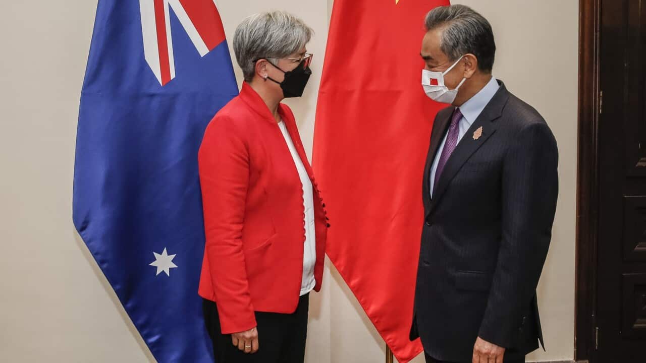 Foreign Minister Penny Wong and China's Wang face each other wearing face masks