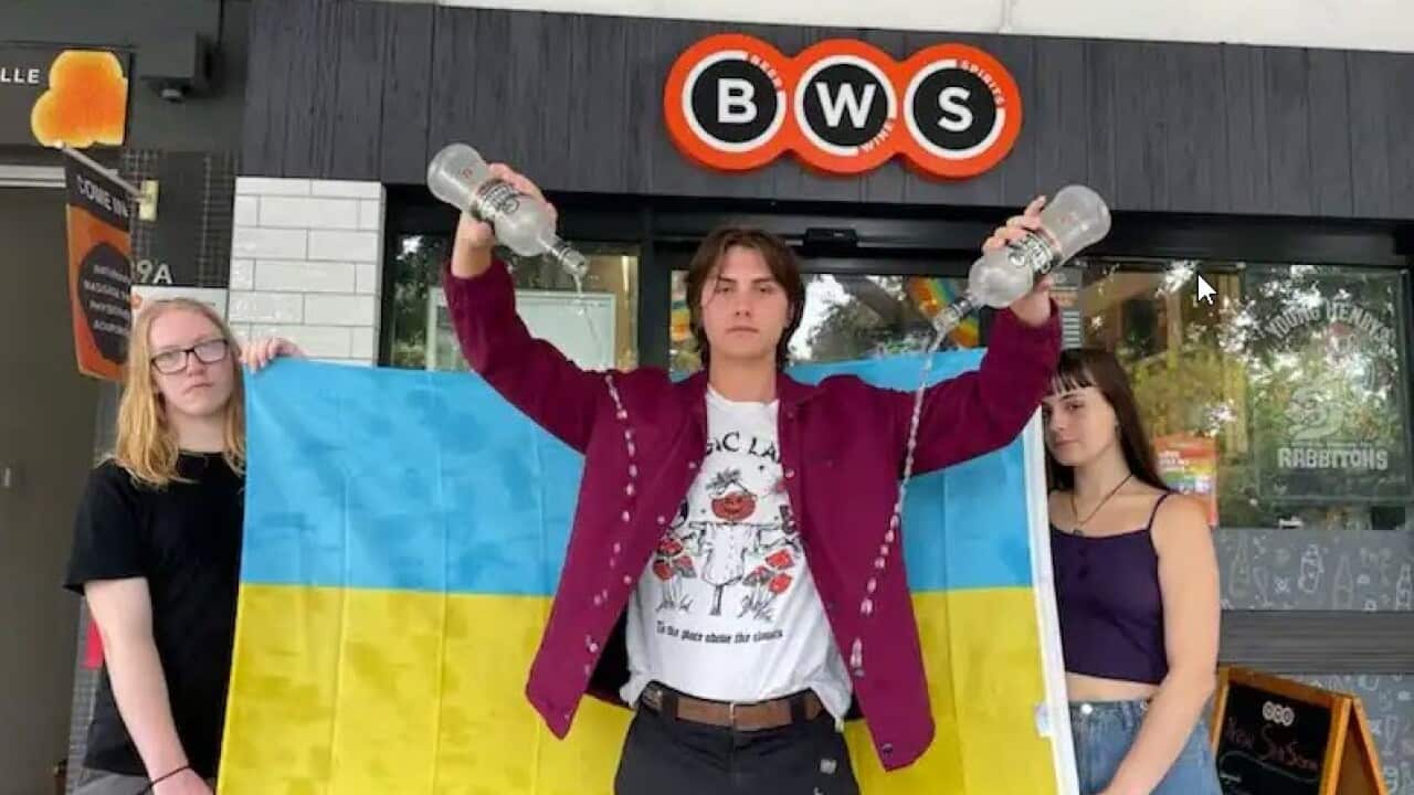 Seb Richardson, Max O'Keefe and Ella O'Shea empty bottles of Russian vodka out the front of a BWS store in Erskineville NSW on Tuesday 1 March
