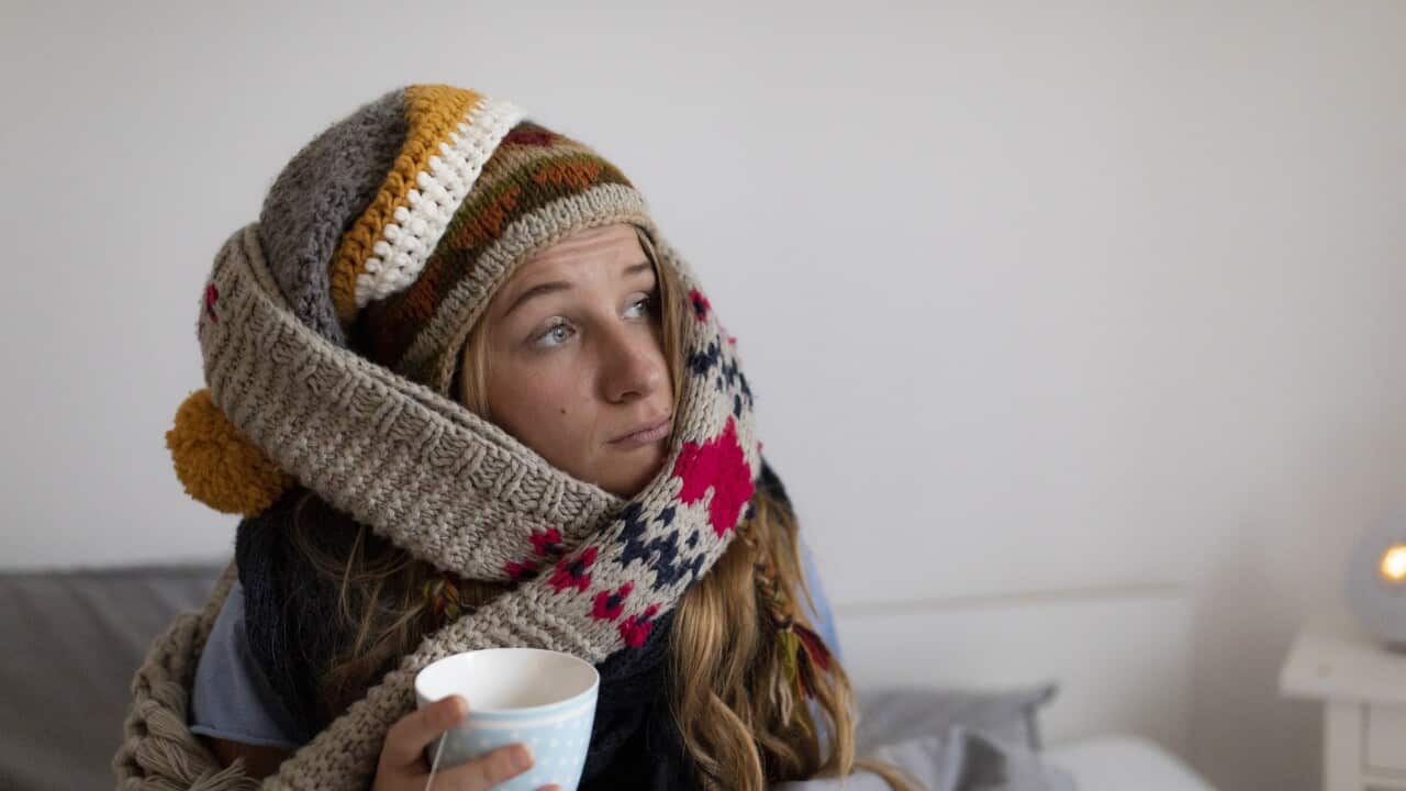 Ill young woman drinking tea in bed at home